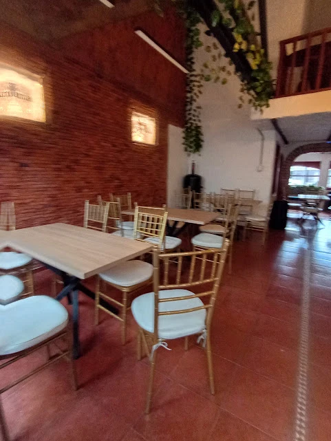 Salón principal con muros de ladrillo y sillas tiffany